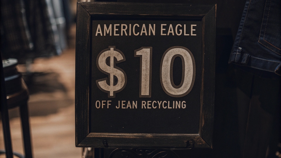 A store sign explaining the American Eagle $10 off jean recycling offer