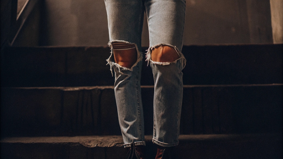 An image capturing the iconic 90s grunge style, with a focus on a pair of light-wash, knee-ripped jeans