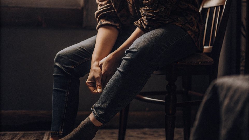 Leg Aches Caused by Tight Jeans A person sitting down and massaging their aching legs after wearing tight jeans