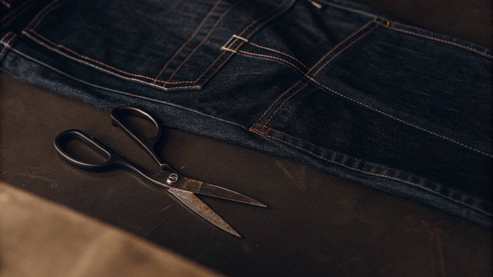 A pair of scissors next to a pair of jeans with a chalk line marked on the leg