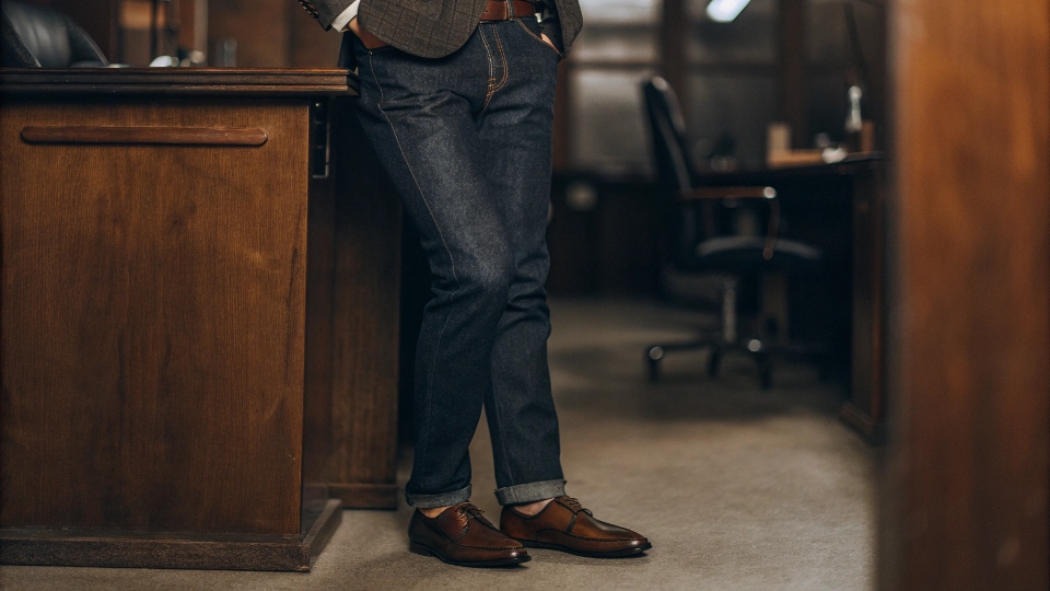 Business Casual Outfit with Jeans A person wearing dark wash jeans with a blazer and loafers in an office setting
