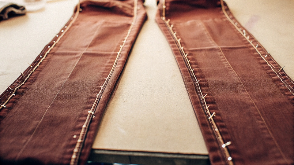 A pair of skinny jeans with pins along the ankle seam, ready for alteration