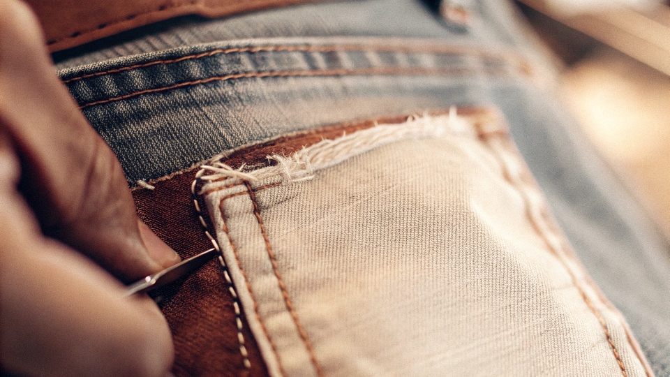 Mending and Sewing Holes in Jeans A close-up of a neatly patched hole in a pair of jeans with decorative stitching