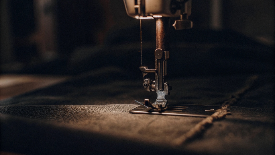 A sewing machine stitching a custom brand label onto an unbranded t-shirt