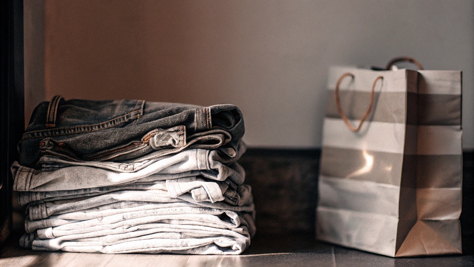 A stack of old jeans next to an American Eagle shopping bag