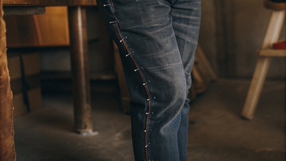 Pinning Jeans for DIY Tapering A person wearing jeans inside-out with pins along the inner leg seam to mark a new, slimmer line