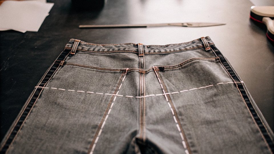 A pair of jeans with a line drawn across the legs, ready to be cut into a skirt