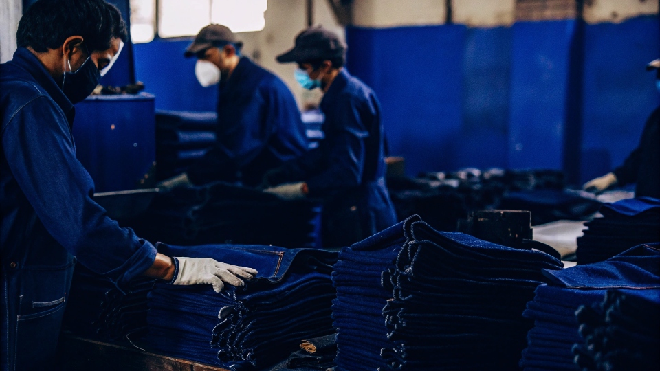 Denim factory workers wearing safety masks and gloves while working