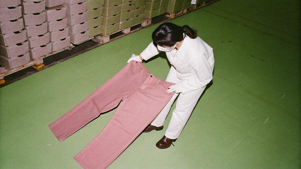 A third-party inspector from SGS examining jeans in a factory warehouse before shipment
