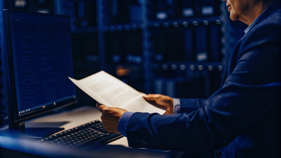 Verifying Translation Accuracy of Documents An experienced manager reviewing bilingual documents side-by-side on a monitor, ensuring they match perfectly.