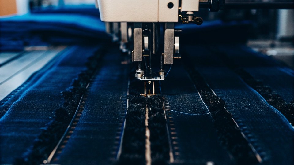An automated sewing machine creating a long, perfect seam on a denim leg