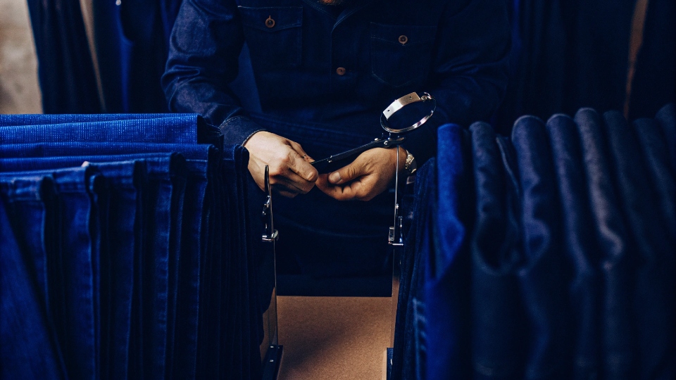 Re-testing Jeans Samples for Repeat Orders A quality control manager meticulously comparing two jeans samples—a new one and an old one—side-by-side.