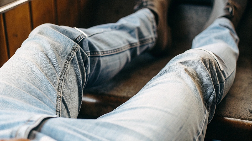 Personalized Fades on Broken-In Raw Denim A pair of well-worn raw denim jeans showing distinct "whisker" fade lines across the lap.