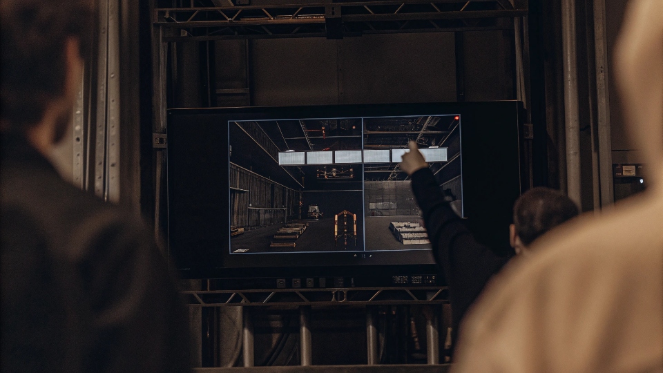 Allocating Machine Hours for Jeans Production A factory production schedule on a large screen, with a manager dragging and dropping a production block to an earlier slot, representing flexibility.