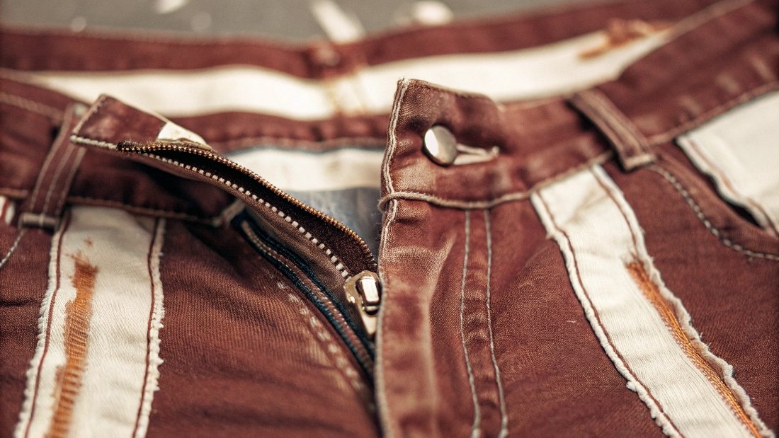 Damage from Washing Jeans Right-Side Out A faded pair of jeans showing prominent white streaks along the seams and zipper area.