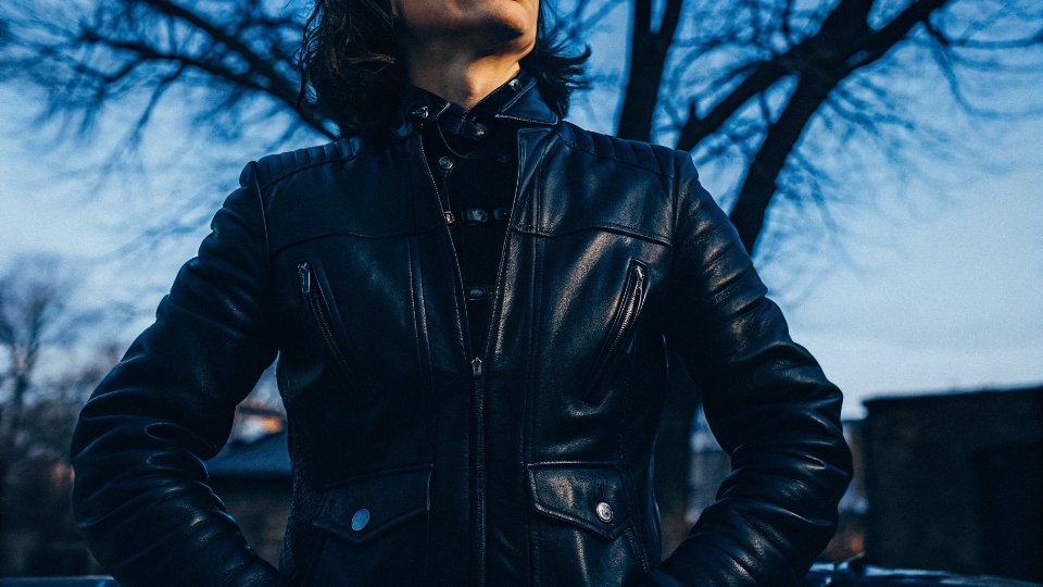 Leather vs Denim Warmth Comparison A person in a leather jacket looking warm and comfortable in a windy, cold setting.