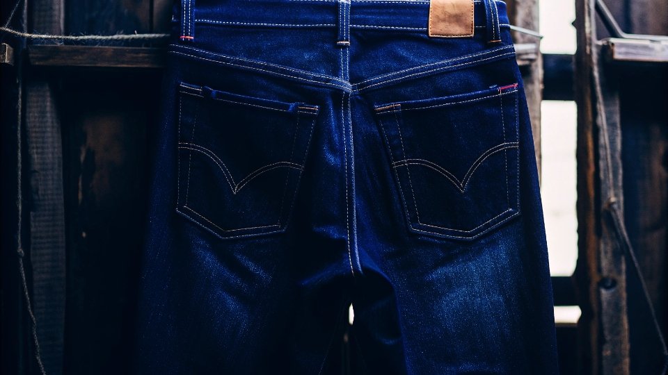 The Iconic Levi's 501 Jeans A classic pair of Levi's 501 jeans hanging against a rustic wooden background.