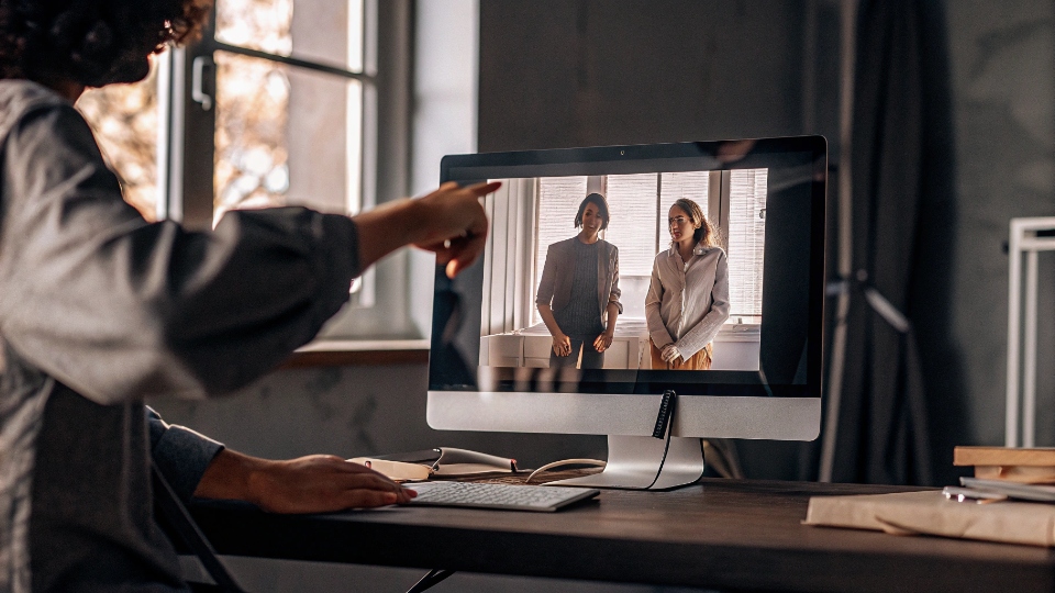Locking in Jean Designs with Factory A designer on a video call, pointing to a tech pack on their screen while a factory manager nods in agreement.