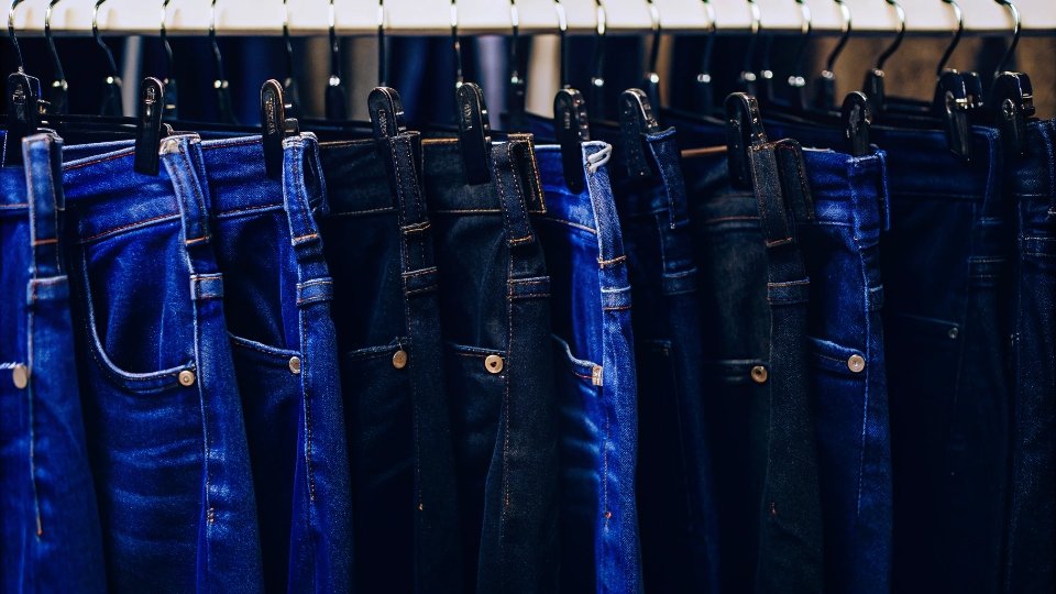 Companies That Make Button Fly Jeans A rack of jeans from different brands, all featuring a button fly.