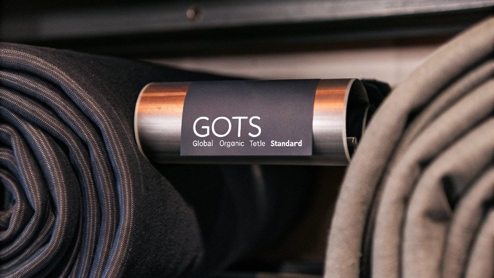 Sourcing Certified Organic and Recycled Denim A close-up of a roll of denim fabric with a visible GOTS (Global Organic Textile Standard) certification tag