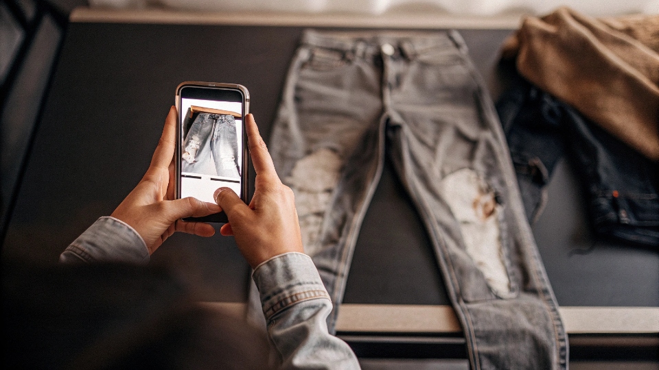 Submitting a Defect Claim for Custom Jeans A person taking a clear photo of a flaw on a pair of jeans with their smartphone to submit a claim.