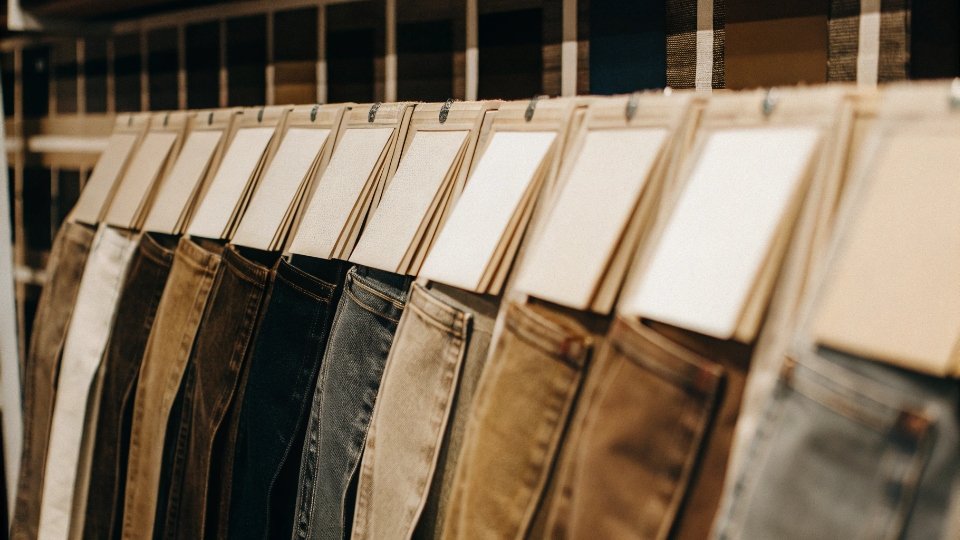 Custom Jean Samples for B2B Buyers A close-up of a sample rack showing a variety of denim washes, from dark raw to light acid wash.