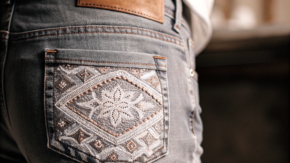 High-Quality Embroidery on Denim Jeans A close-up of a beautifully executed, complex embroidery design on the back pocket of a pair of jeans.