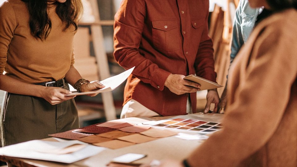 Pre-Production Meeting for Jeans Manufacturing A team of designers and factory managers gathered around a table with fabric swatches, tech packs, and a sample garment.