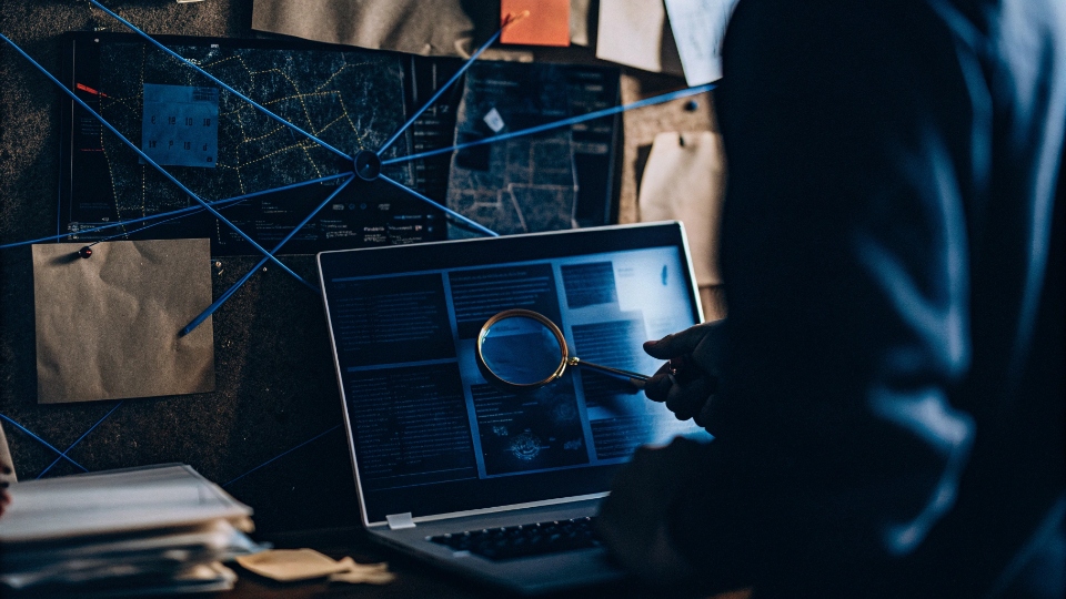 How to Find What Manufacturer a Brand Uses A person working like a detective, with a laptop showing import data and connecting pins on a corkboard.