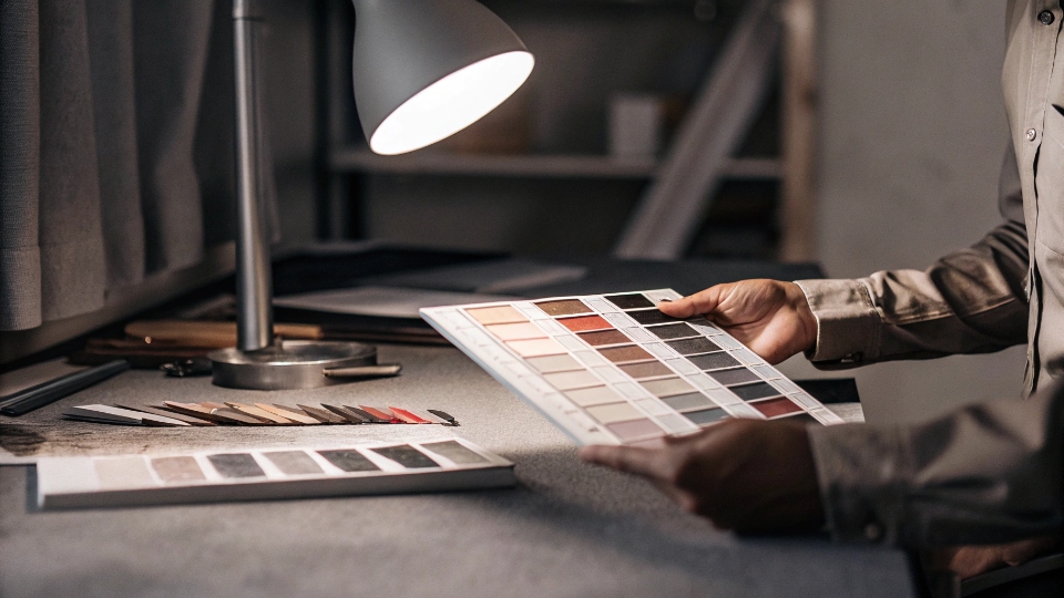 Color Matching Fabric Swatches Under Daylight Lamp A quality control expert comparing a new fabric swatch to a master color standard under a professional daylight lamp.