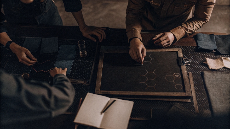 Denim Wash R&D Support Team A team of R&D engineers collaborating around a table, looking at denim swatches and chemical formulas