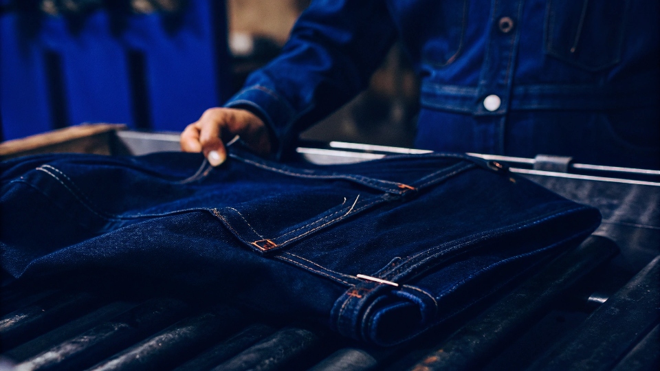 Durable RFID Tag After Industrial Wash A jean with an RFID tag being removed from a heavy-duty industrial washing machine, the tag still looking pristine.