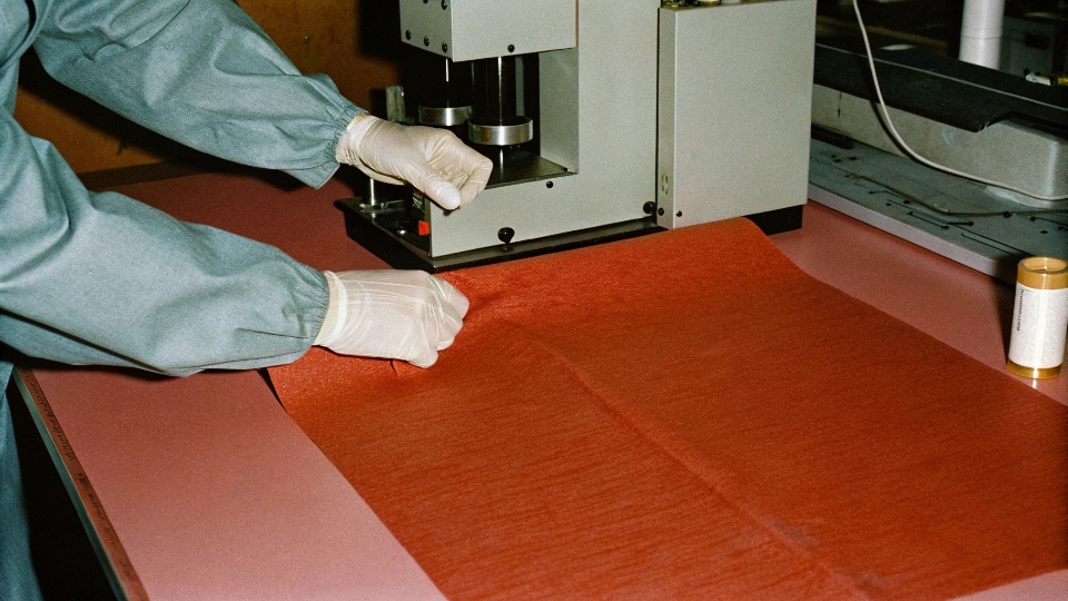 A lab technician performing a colorfastness test on a denim fabric swatch