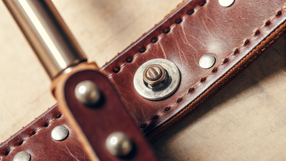 Custom Jean Hardware with Warranty Coverage A close-up shot of high-quality custom jean hardware, including a branded button and rivets, shining under a light.