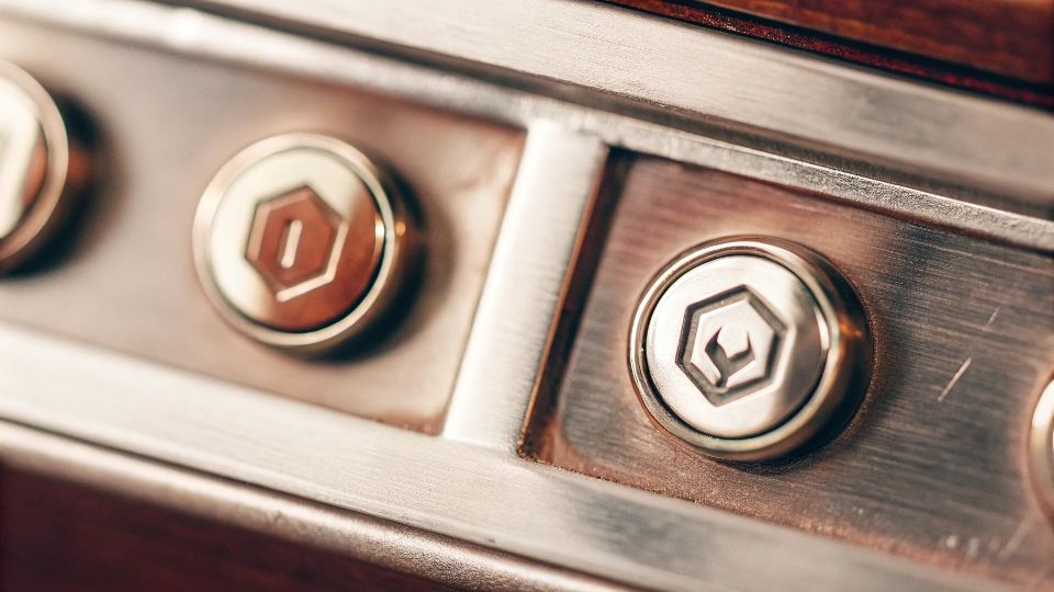 Custom Co-Branded Button Tooling A close-up of a custom-molded metal button featuring two small, distinct logos.