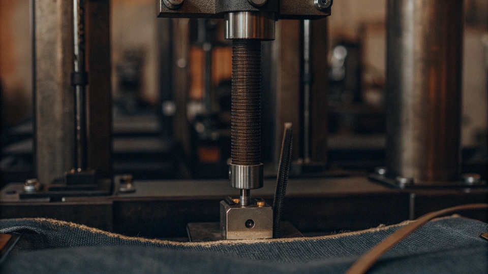 Testing Zipper Smoothness and Locking Strength A lab machine testing the locking strength of a jean zipper with a digital readout