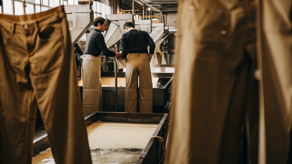Scaling Denim Wash from Lab to Bulk Production A production line with quality control inspectors checking jeans for wash consistency at different stages