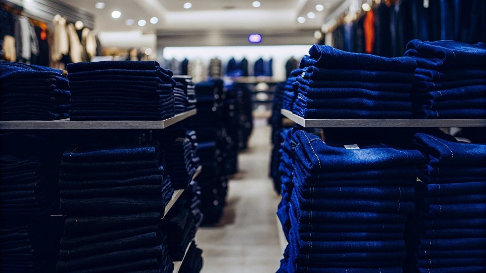 Mass-Market and Fast-Fashion Jeans Sales Stacks of jeans in a brightly lit fast-fashion retail store.