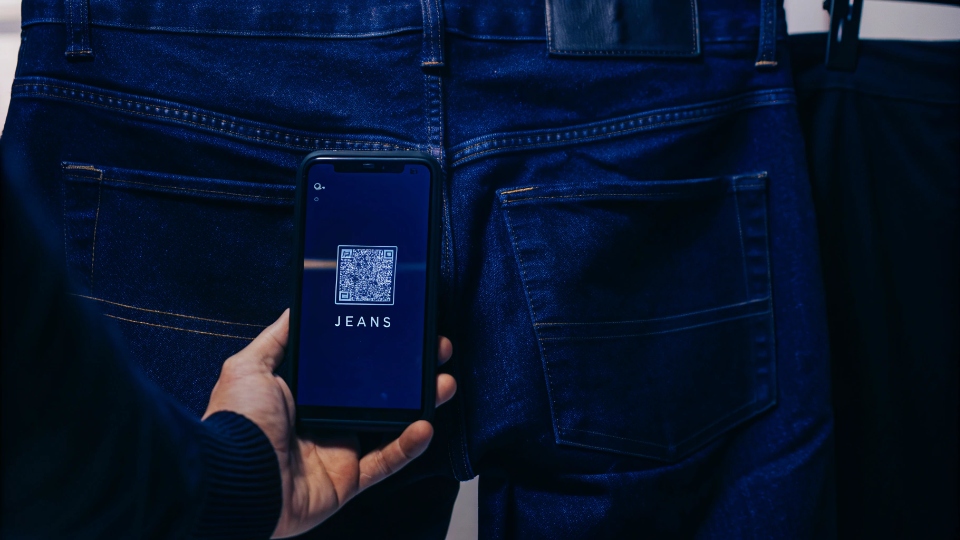 Scanning QR Code on Jeans for Brand Story A smartphone scanning a QR code on a jeans label, revealing a brand story on the screen.