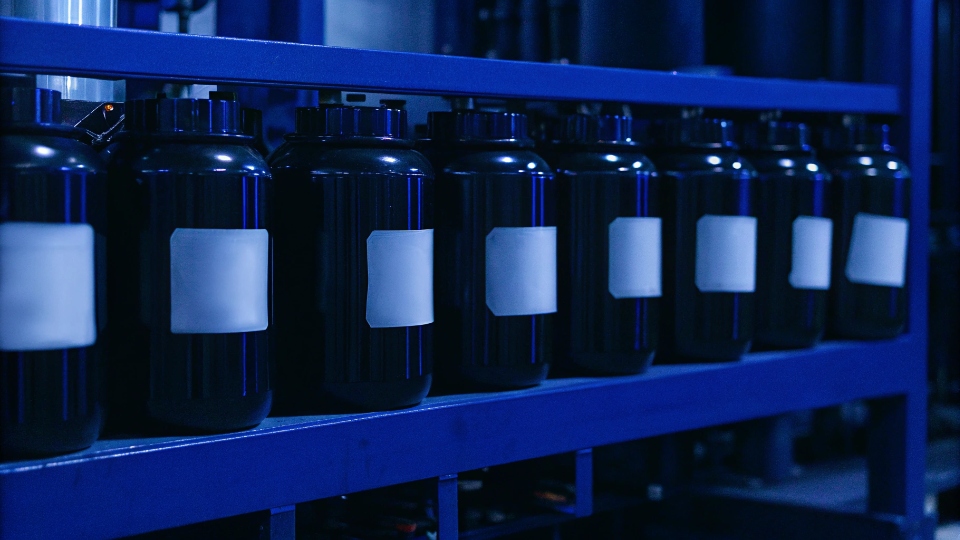 A shelf with multiple labeled chemical containers used in a denim factory