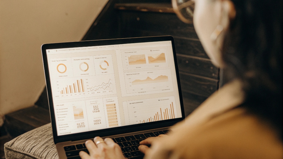 Real-Time KPI Dashboard for Jeans Production A person looking at a laptop screen displaying a real-time KPI dashboard with production and quality metrics.