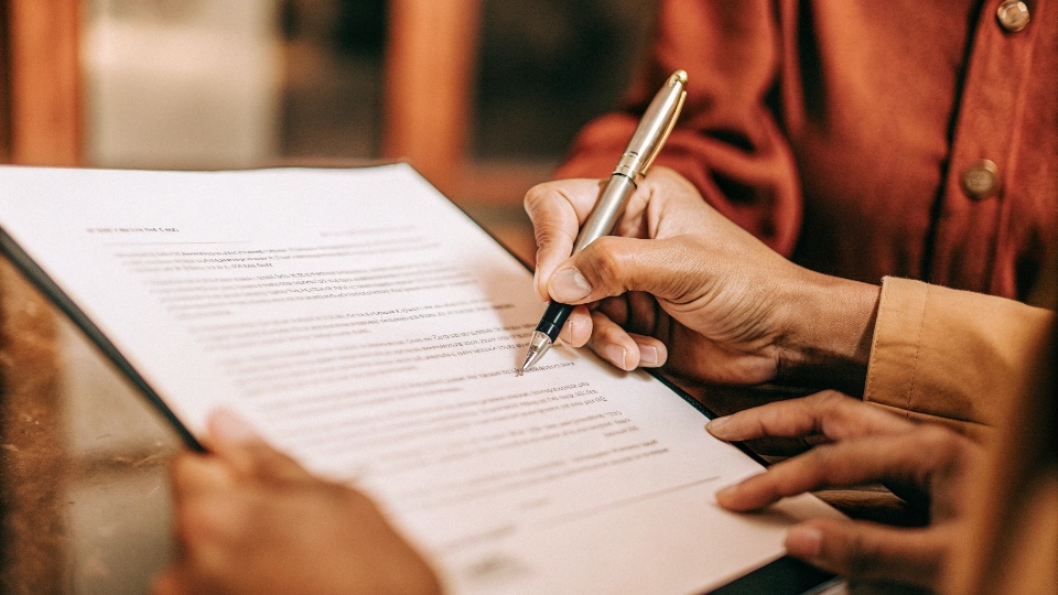Signing a Confidentiality Agreement for Jean Designs A close-up of a person signing an NDA document with a pen