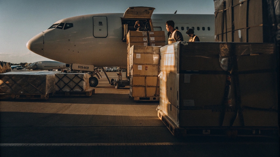 Air Freight Shipping for Pilot Run Jeans An express air freight cargo plane with boxes being loaded at an airport tarmac.