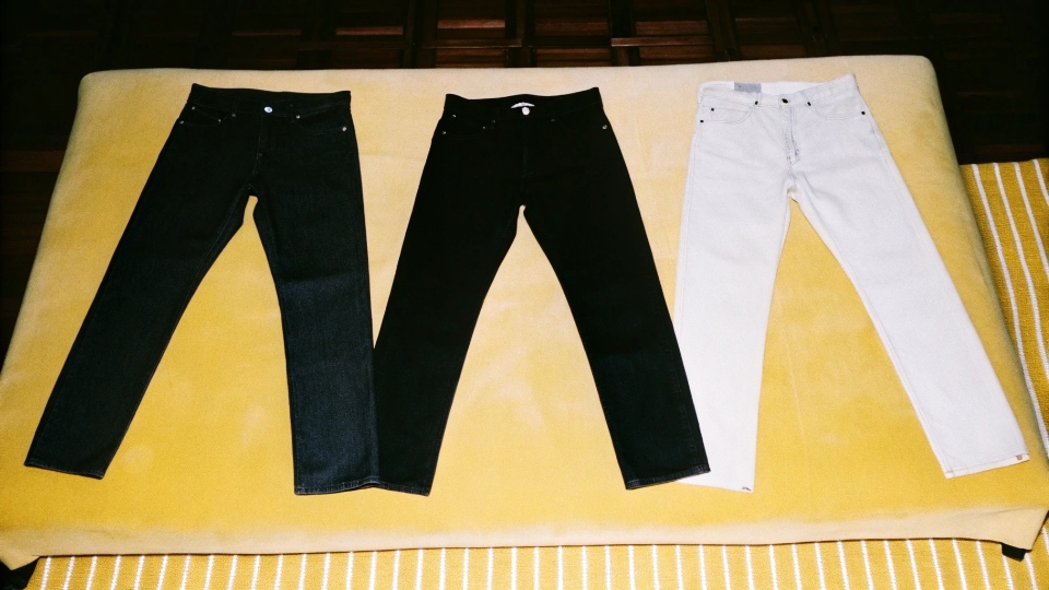 Combining Jean Styles to Meet MOQ Three different styles of jeans laid out, all made from the same dark denim fabric