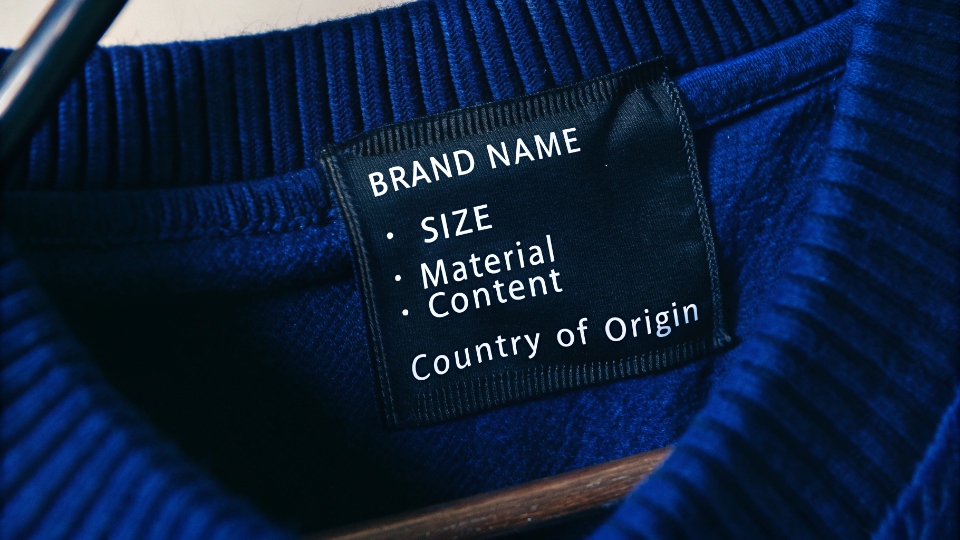 Legal Requirements for Clothing Labels A close-up of a custom clothing neck label showing the brand name, size, material content, and country of origin.