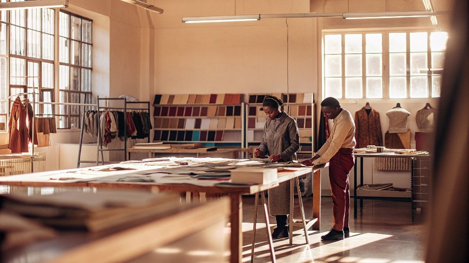 Private Showroom for B2B Jeans Buyers A bright, modern factory showroom with racks of custom jean samples and a large table with fabric swatches.