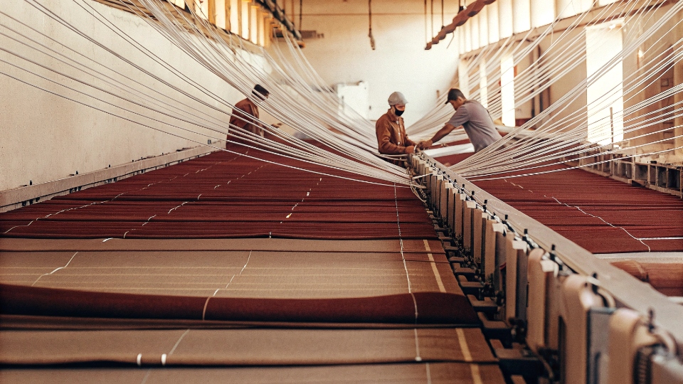 Scaling Jeans Production Lines Smoothly An assembly line for jeans, starting with a few workers on one end and expanding to multiple lines of workers at the other end, showing a smooth scale-up.
