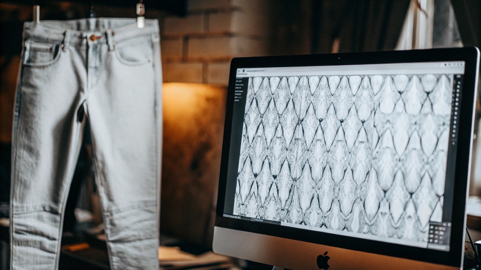 From Digital Design to Precise Laser Whiskers A computer screen showing a vector design file of a whisker pattern next to the finished jean with the identical laser-etched pattern.