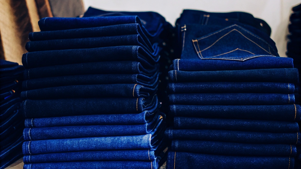 Reputable Jeans Manufacturers A collection of high-quality denim jeans neatly folded in a stack.