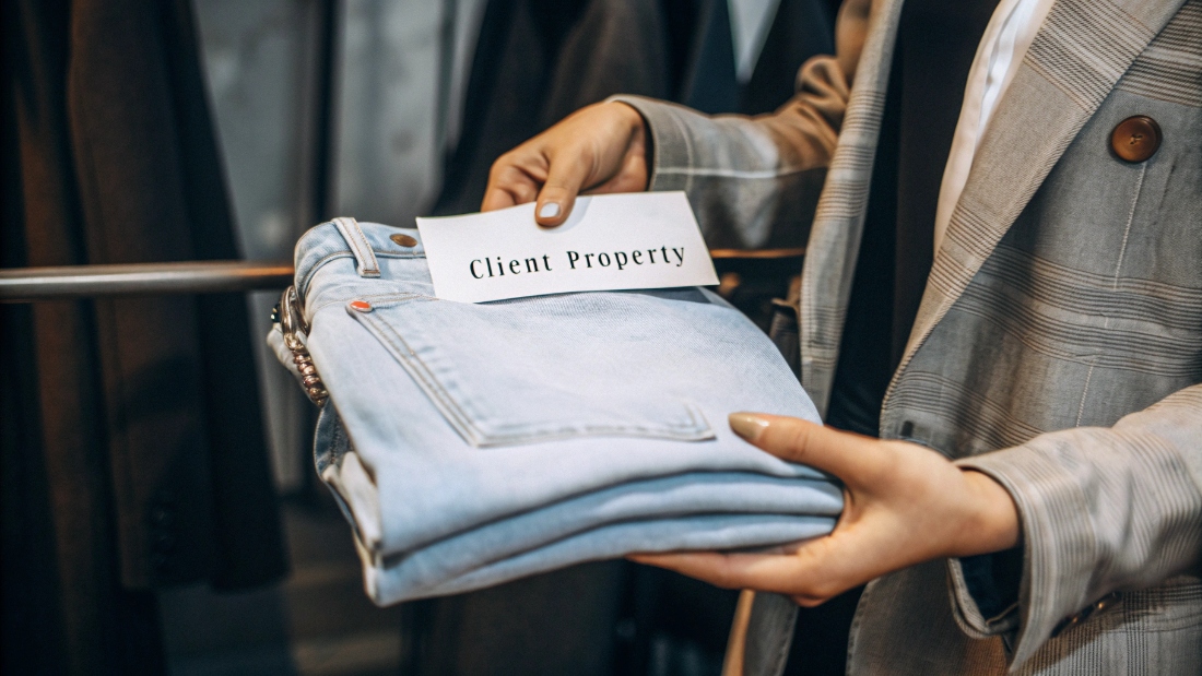 Client Ownership of Jean Prototypes A designer holding a fit sample of a jean with a tag that says "Client Property"